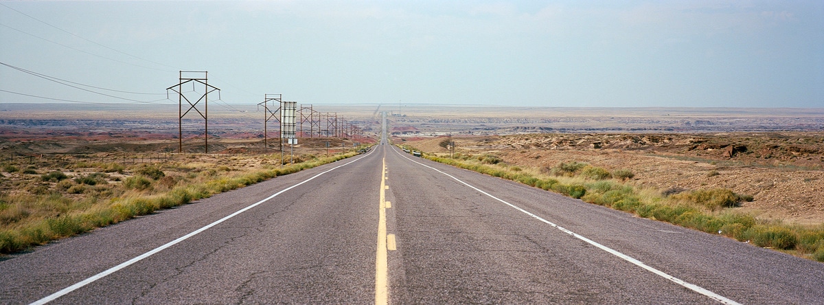 Long stretch of road show the emptiness of the desert in New Mexico, USA. Taken by Lucas Taylor on a Hasselblad XPan camera.